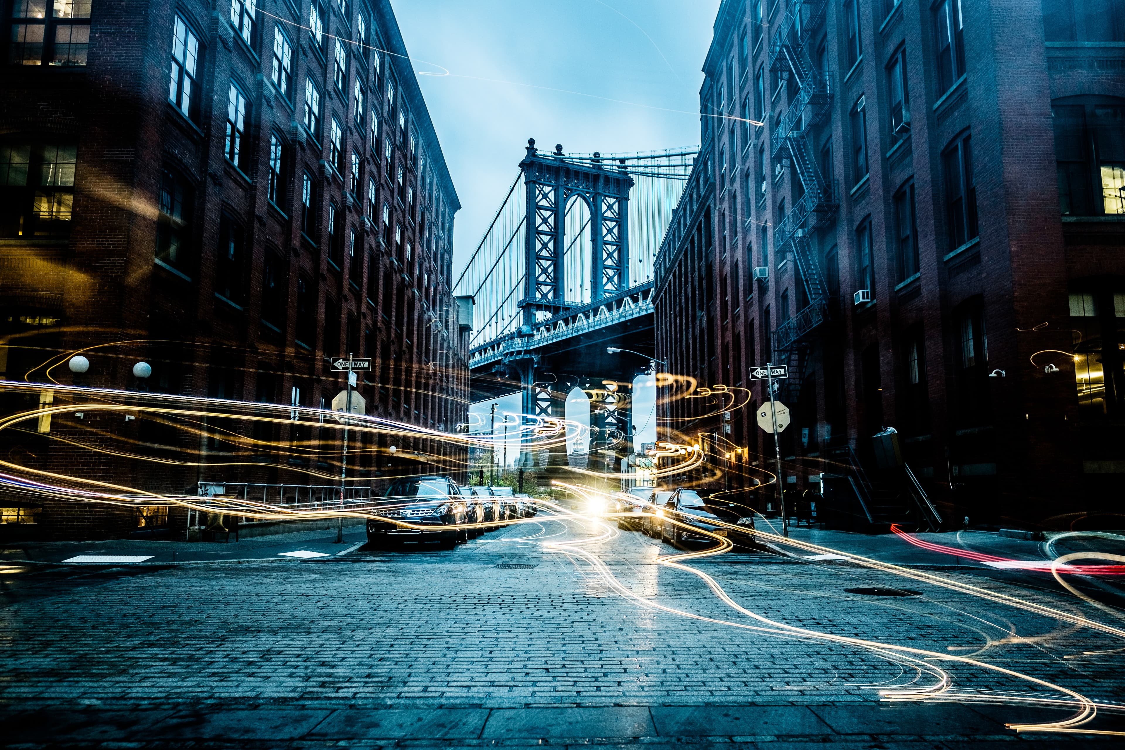 City street at night with light trails and bridge architecture
